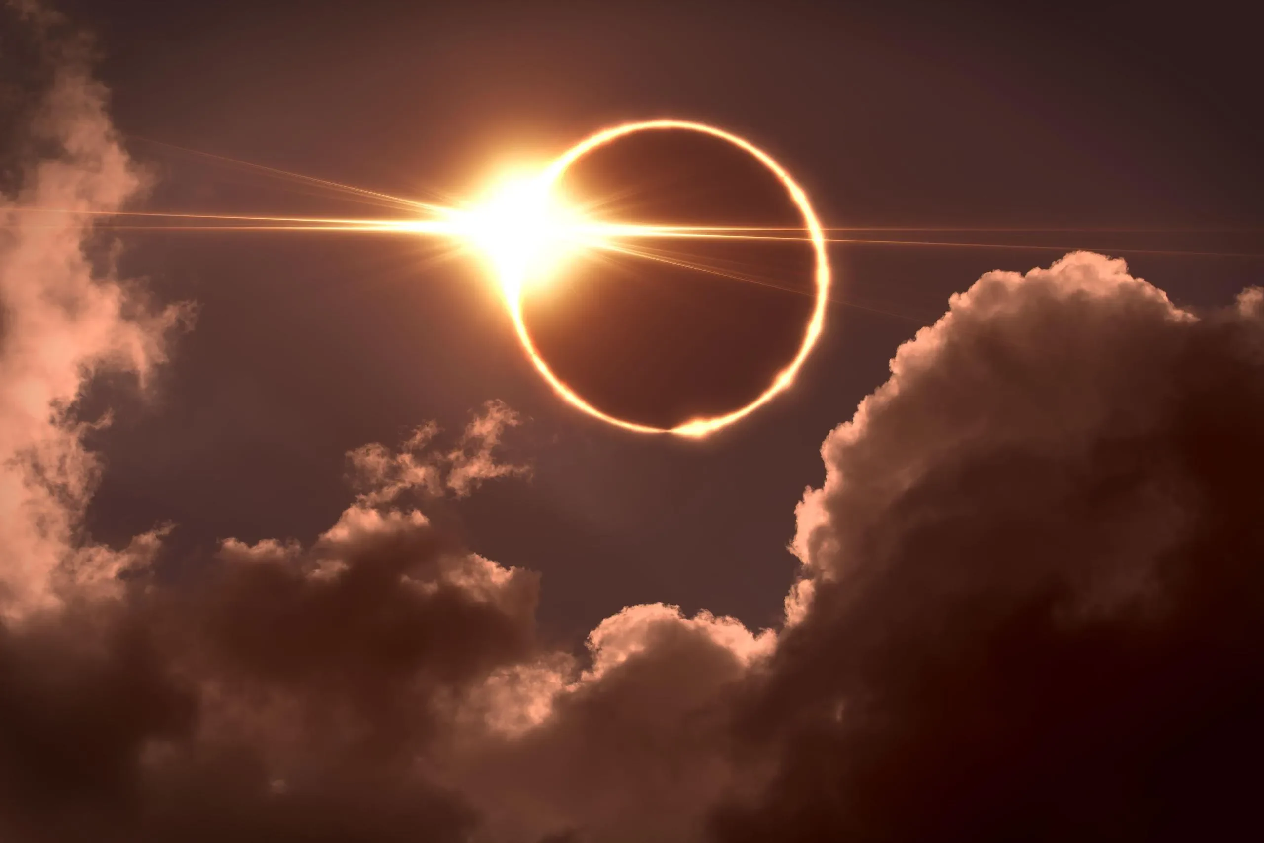 Total solar eclipse with sun rays through clouds